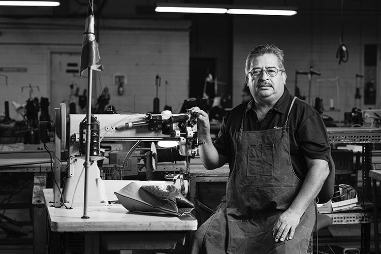 A Hispanic man wearing a polo shirt and an apron looks into the camera.